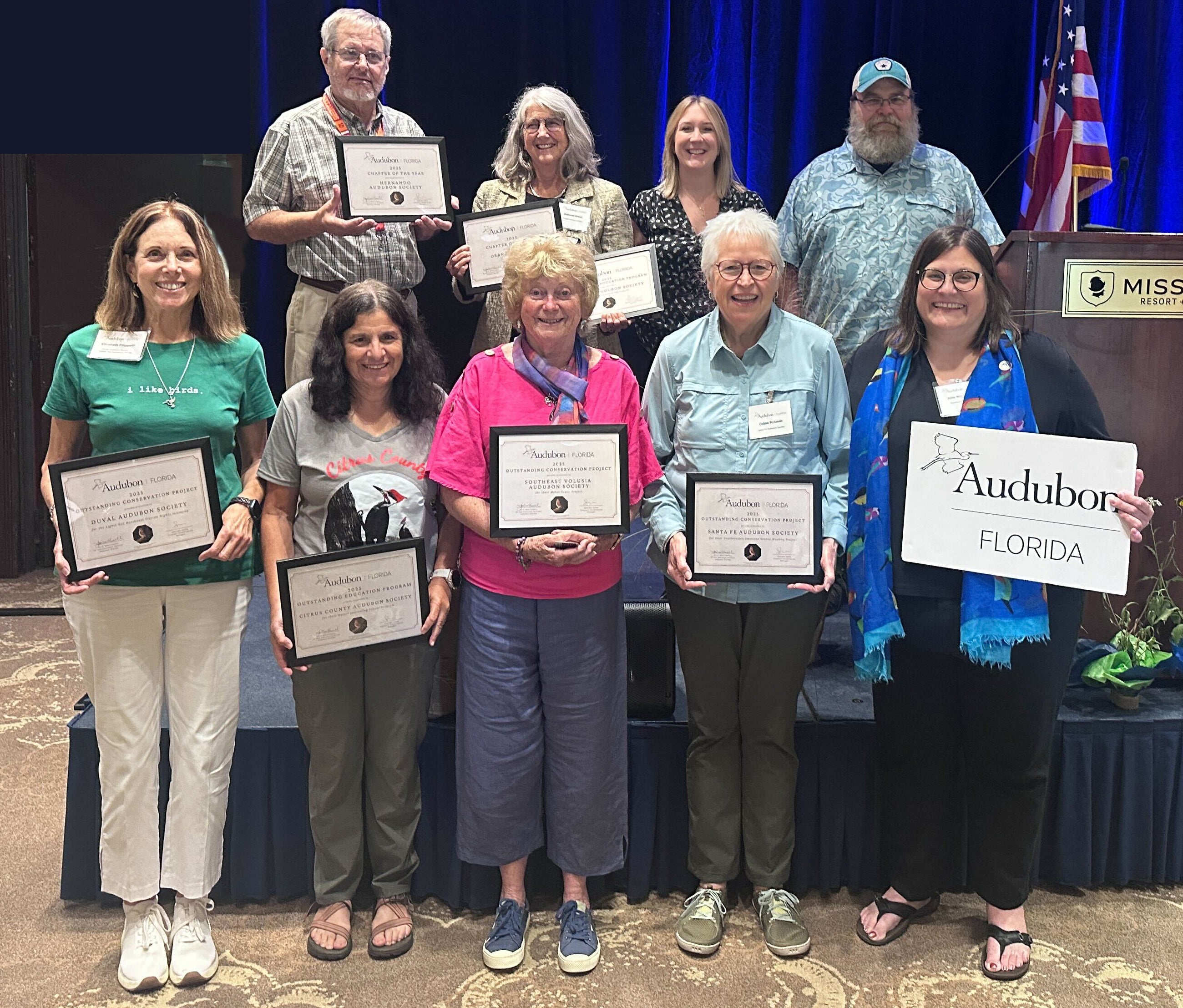 Nine people holding awards pose for the camera